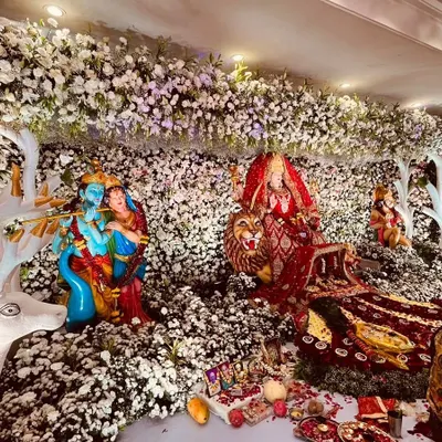 A breathtaking floral installation featuring idols of Radha-Krishna and the Goddess, set within a forest of white flowers and artistic deer figures. We design and execute elaborate thematic decor for devotional events.