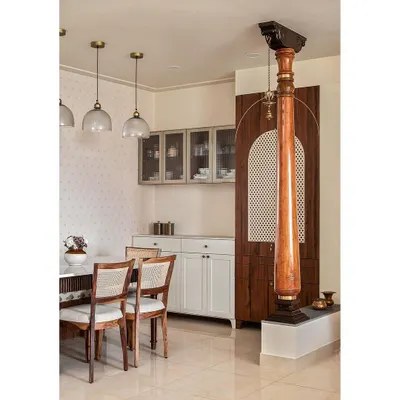 This dining area pays homage to the client's heritage with traditional wooden columns and a 'katte' bench. A discreet puja unit is hidden behind CNC jali doors, seamlessly integrating spirituality into the design.