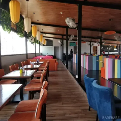 We have been designing spaces you love for a long time, like this project for Gilly's. The interior features a mix of colorful seating, warm wood tones, and industrial elements to create a fun and inviting atmosphere.