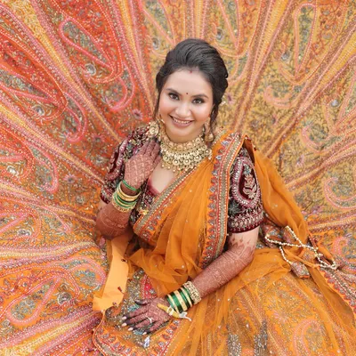 A breathtaking full-length shot of my bride in her stunning orange lehenga. I aimed for a look that was as grand and beautiful as her attire, focusing on radiant skin and classic bridal makeup.