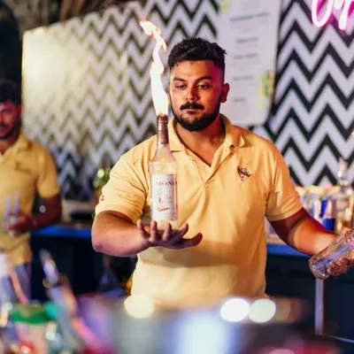 A flair bartender balances a bottle while expertly handling another lit with fire. This is the level of skill and showmanship we bring to every event.