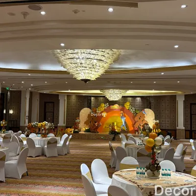 A wide view of the entire banquet hall transformed for a Lion King celebration. The grand stage is the focal point, with themed tables ready for guests to enjoy the party.