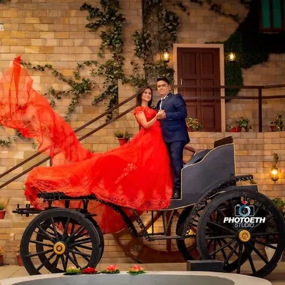 A fairytale moment brought to life with a vintage horse-drawn carriage. The bride's dramatic red gown flows beautifully, creating a stunning, high-fashion pre-wedding photograph.