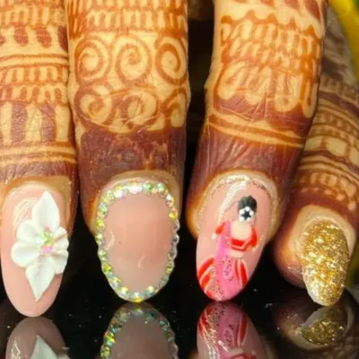 A close-up of the incredible detail on a bridal nail set, featuring a hand-painted bride, a 3D white flower, a full rhinestone border, and a gold glitter accent nail.