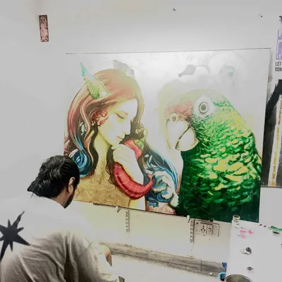 A view from behind my shoulder as I work on the fine details of this large parrot painting. Creating art is a meditative process that requires immense focus and patience.