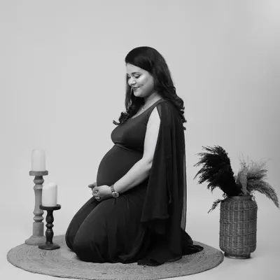 A quiet and soulful black and white portrait. This image focuses on the beautiful shape of the baby bump and the mother's serene expression, creating a timeless piece of art.