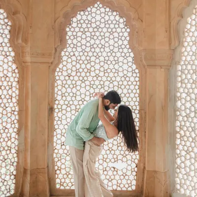 A tender embrace framed by a magnificent latticed archway in Jaipur. We masterfully use natural light and architecture to create these breathtakingly romantic and timeless pre-wedding portraits.