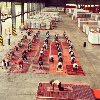 Leading a large corporate yoga class at a Coca-Cola distribution warehouse. This wide shot shows me guiding dozens of employees through a gentle warm-up, bringing a moment of calm to their busy workday.