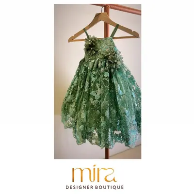 A clear view of a custom-designed birthday dress in an elegant green net fabric. This piece features intricate floral embroidery and delicate 3D flower appliqués on the bodice, creating a truly magical look for a special celebration.