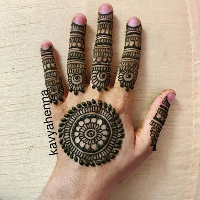 A classic mandala, or gol tikki, design on the palm. This minimalist style is complemented by detailed patterns on each finger, making it a popular choice for parties and festivals.