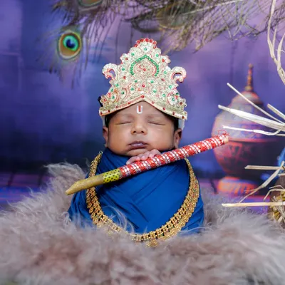 My little Krishna. This is one of my most requested themes. This newborn is dressed as Lord Krishna with a crown and flute, sleeping peacefully against a divine backdrop.