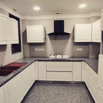 This is the finished U-shaped kitchen in our Gurgaon DLF project. The classic white cabinets provide ample storage, while the granite countertop and floor are chosen for their durability and ease of maintenance.