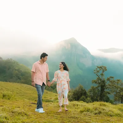 A couple walks hand-in-hand against a stunning backdrop of misty mountains. This is the kind of epic, scenic pre-wedding photography I specialize in.