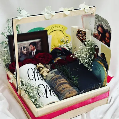 Celebrate their special day with a romantic anniversary hamper. This beautiful pinewood basket is filled with a personalized "Mr & Mrs" mug, a photo frame, fresh red roses, cookies, and other treats.