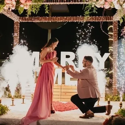 The perfect moment. We created this romantic setup with a rustic brick-textured arch, soft florals, and dramatic cold pyros to make this surprise proposal an absolutely unforgettable memory.