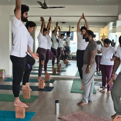 Our gurus are always present on the mat, offering verbal cues and physical adjustments. Here, a teacher guides students through a standing balance sequence, ensuring stability and correct form.