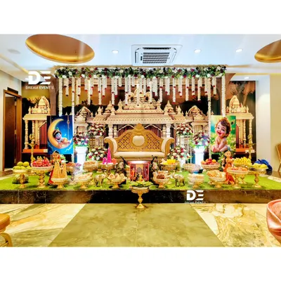 A truly grand and royal baby shower setup designed to look like a temple gopuram. The stage is filled with traditional offerings, Marapachi dolls, and a regal seat for the mother-to-be.
