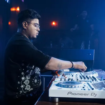 A side profile of me focused on the mix. The blue-lit, smoky atmosphere of the club provides the perfect backdrop for a night of deep house and techno.