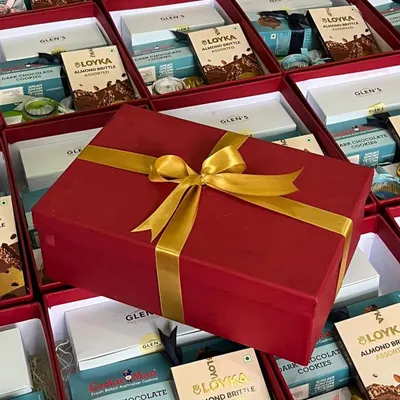 We manage large-scale corporate orders with precision. Here, hundreds of festive gift boxes are being prepared, with one elegant red and gold box highlighting the final presentation.