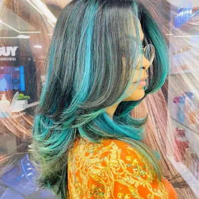 This is a fantastic example of our creative color work. The vibrant turquoise highlights are expertly blended with the client's dark base color for a bold, fashion-forward look.