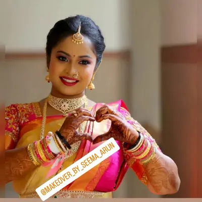 A beautiful, forward-facing portrait of my client ready for her muhurtham. Her makeup features a bright red lip and defined eyes, perfectly complementing her gold choker and maang tikka for a classic bridal photoshoot.