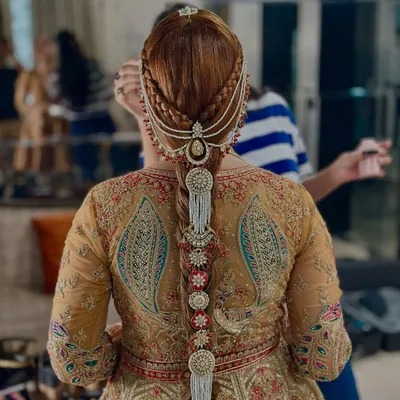 A stunningly detailed traditional braid for a wedding. This look features intricate side braids leading into the main plait, which is heavily adorned with pearl and kundan hair jewelry, including a passa.