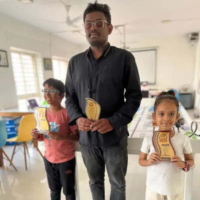 Two of our young champions proudly display their trophies from the Codeavour 6.0 robotics competition alongside their mentor. This highlights our success across different age groups.