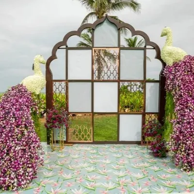 This luxurious photo booth was designed to be a showstopper. It features two large peacocks made from flowers set against a mirrored wall, creating an opulent and unforgettable photo opportunity for guests at a wedding reception.