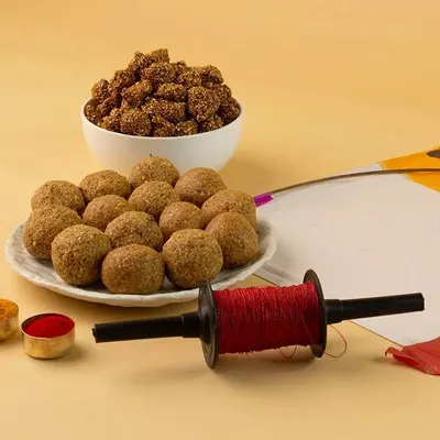 A classic, well-lit photograph capturing the essence of Makar Sankranti. The composition balances traditional sweets like ladoo with festive elements, shot against a warm, seamless beige background to make the colors pop.