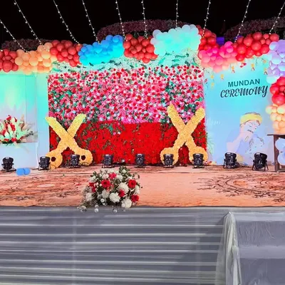 A fun and colorful stage for a Mundan ceremony. I created a backdrop with a wall of red and pink flowers, a balloon arch, and large custom cutouts of scissors to fit the theme perfectly.