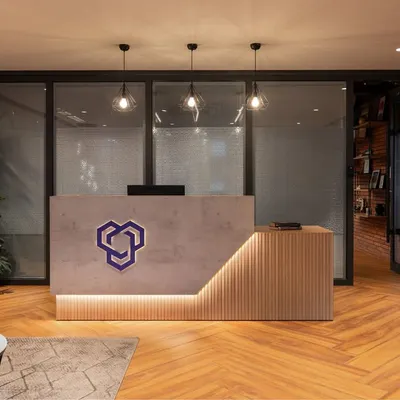 The reception desk at YOUNION Office, where a concrete-finish desk with integrated lighting and herringbone wood floors create a modern and welcoming first impression.