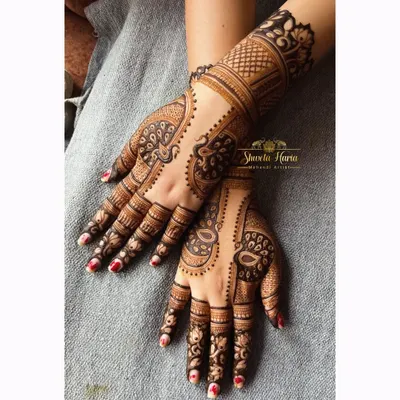 A fancy back-hand henna design featuring graceful peacock motifs. The use of negative space and detailed feather work makes the peacocks stand out beautifully.
