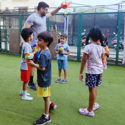 Here I am with one of my groups, getting ready for a ball game on the turf. I make sure every session has a low coach-to-child ratio, so I can give each child the attention they need to learn, play, and feel included in the fun.