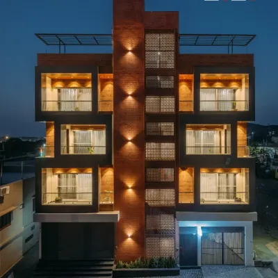 A full view of our Pushkar residential project, highlighting the symmetrical design and material palette. The warmth of the brick-clad central column contrasts with the sleek, dark frames of the recessed balconies. This balance of materials and form gives the building a distinct and grounded presence.