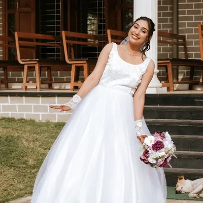 A joyful Catholic bride, Priyanka, in her beautiful white gown, holding a bouquet. Her makeup is fresh, radiant, and picture-perfect.
