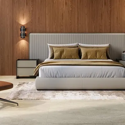 This minimal bedroom design combines a plush upholstered bed with a warm wood accent wall and a comfortable leather reading chair. The result is a sophisticated and calming space that feels like a luxury hotel suite.