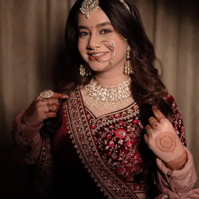 A happy bride showing off her intricate henna and stunning jewelry. This mid-shot captures her personality and the beautiful details of her velvet blouse and heavy embroidery, a perfect memory from her wedding day.