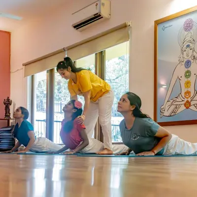 An instructor offers gentle guidance during Cobra Pose, ensuring young practitioners learn with proper form. Our hands-on approach helps children build a strong and safe foundation in their asana practice.