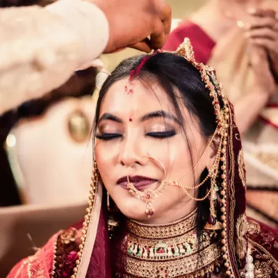 A close-up shot of the sindoor daan, one of the most significant moments in a Hindu wedding. I focus on the bride's serene expression as the vermilion is applied, capturing the deep emotion and sanctity of this ritual.