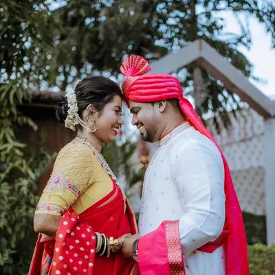 A sweet and romantic moment between a newly married couple. The groom wears a vibrant pink pheta, and their gentle forehead touch captures the love and happiness of the day.