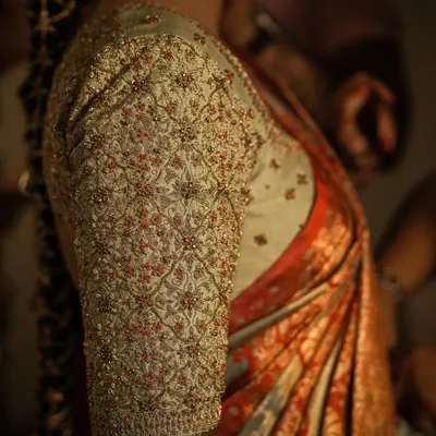 A detailed close-up of a fully embroidered blouse sleeve. The intricate jaal pattern is created with dense beadwork and thread, demonstrating the level of precision in my handwork for bridal couture.