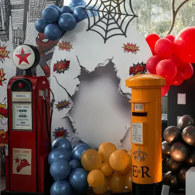 POW! This Spider-Man themed photo booth is ready for action, featuring a broken-wall effect, a spider web, and classic comic book sound effects.