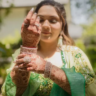 A close up of the bride admiring her intricate mehndi design. We focus on capturing the artistry of the henna and the bride's happy anticipation.