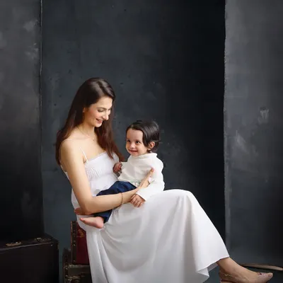 A mother and her child share a gentle moment against a dark, textured backdrop. This painterly style emphasizes emotion and connection, creating a portrait with depth and artistic quality.
