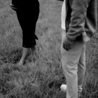 A minimalist black and white shot focusing on the couple holding hands. The simplicity of the image draws all attention to their connection and the baby bump.