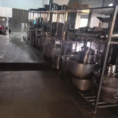 A view of our kitchen's storage area, with large cooking pots and stainless steel racks. The space is designed for efficiency and large-scale food production.