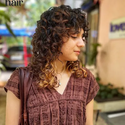 A curly shag with bangs is always a vibe. This cut adds tons of texture and shape, with subtle highlights at the tips to make the layers pop.
