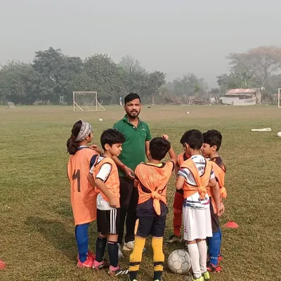 A coach gives instructions to our U8 team during a huddle at a friendly match. We focus on clear communication and building confidence from a young age.