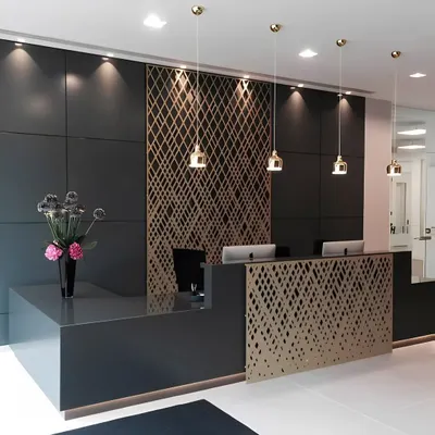 A sleek and modern reception desk designed for a high-end corporate client. The minimalist dark grey desk is accented with a custom-cut gold lattice screen, complemented by elegant pendant lighting and spotlights to create a sophisticated ambiance.