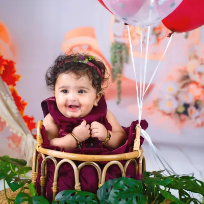 Six months of sweetness! This close-up shot captures the happy, gummy smile of a six-month-old during her half-birthday photoshoot, surrounded by balloons.